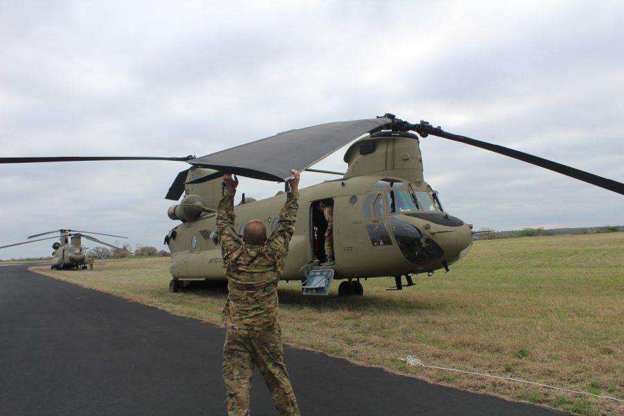 United States National Guard Airman ties down Chinook plane rotors to the ground due to high winds.