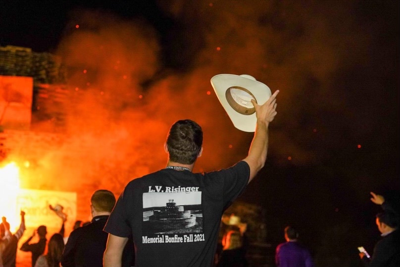 A plowboy standing in front of the L.V. Risinger bonfire.