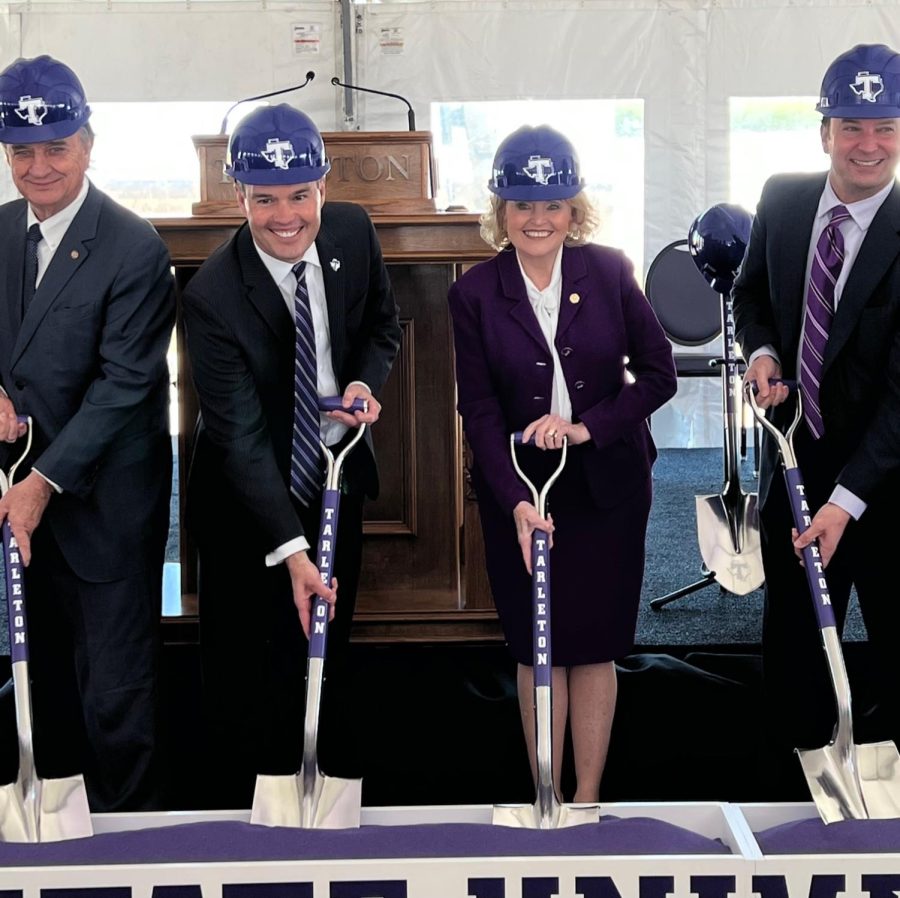 John Sharp, James Hurley, Beverly Powell and Craig Goldman sporting purple hard hats as they begin shoveling into a trough of purple sand.  After the ceremony, guests of the groundbreaking were given glass bottles to fill with the purple “groundbreaking” sand as a way to commemorate the event. 
